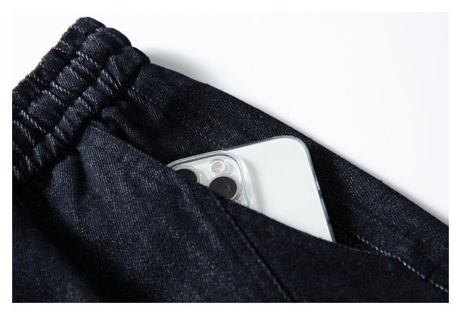 A phone tucked into the pocket of dark indigo pants, shown close up.