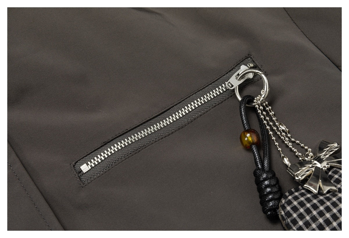 Close-up of a silver zipper and dangling charm on a dark charcoal-brown jacket.