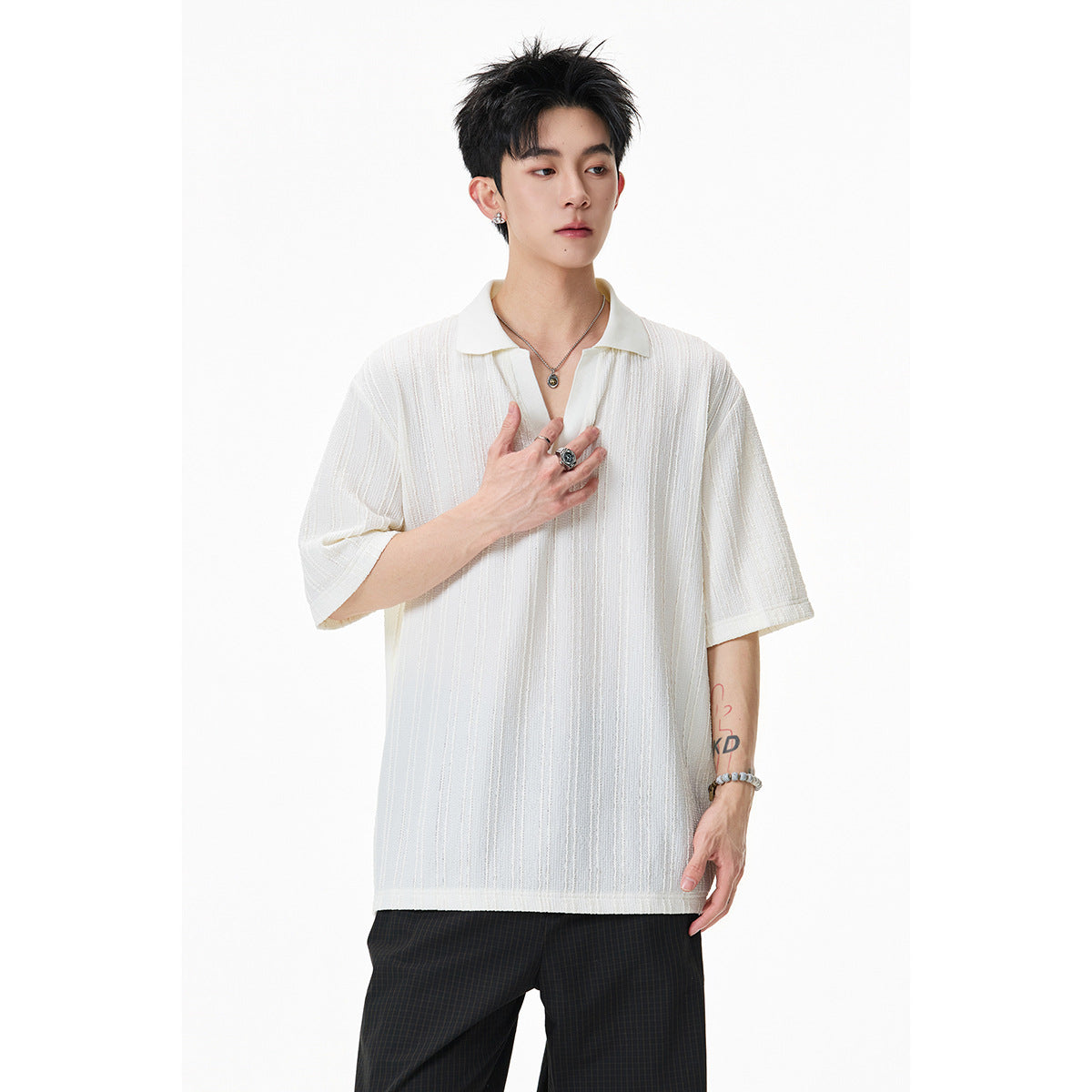 Model wearing an ivory textured short-sleeve polo with dark trousers.