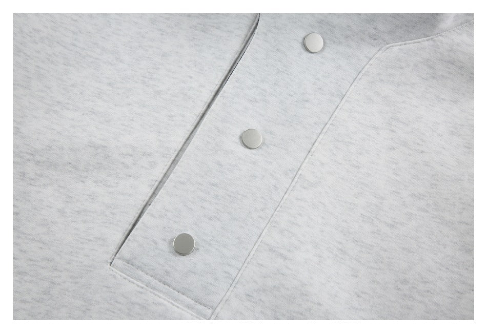 Close-up of three round snaps on the front placket of a light gray marled jacket.