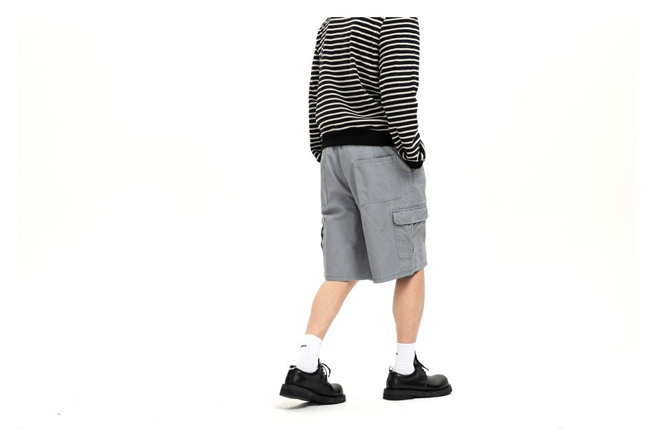 Rear angled view of a model wearing light gray cargo shorts with back and flap side pockets.