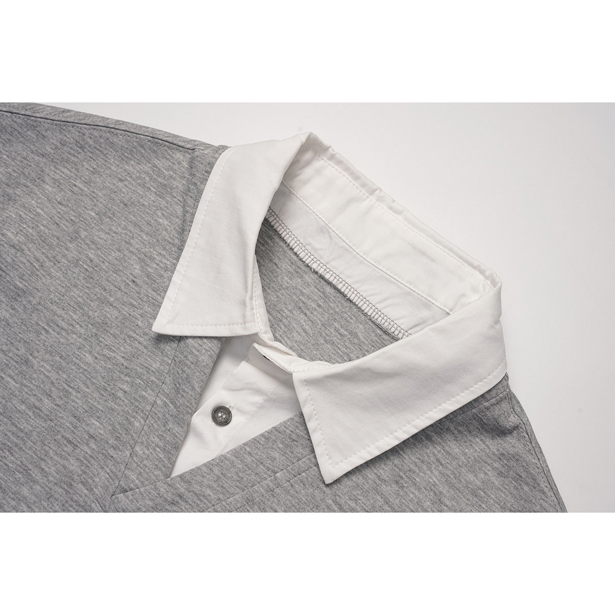 Close-up of a light gray top's white pointed collar and button placket.