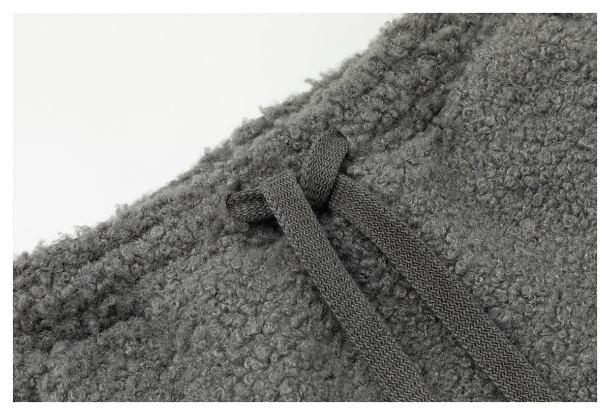 Close-up of dark drawstrings tied at the waistband of a gray loop-textured garment.