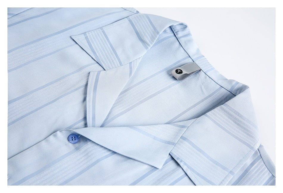 Close-up of a light blue striped shirt collar, placket, and blue button.