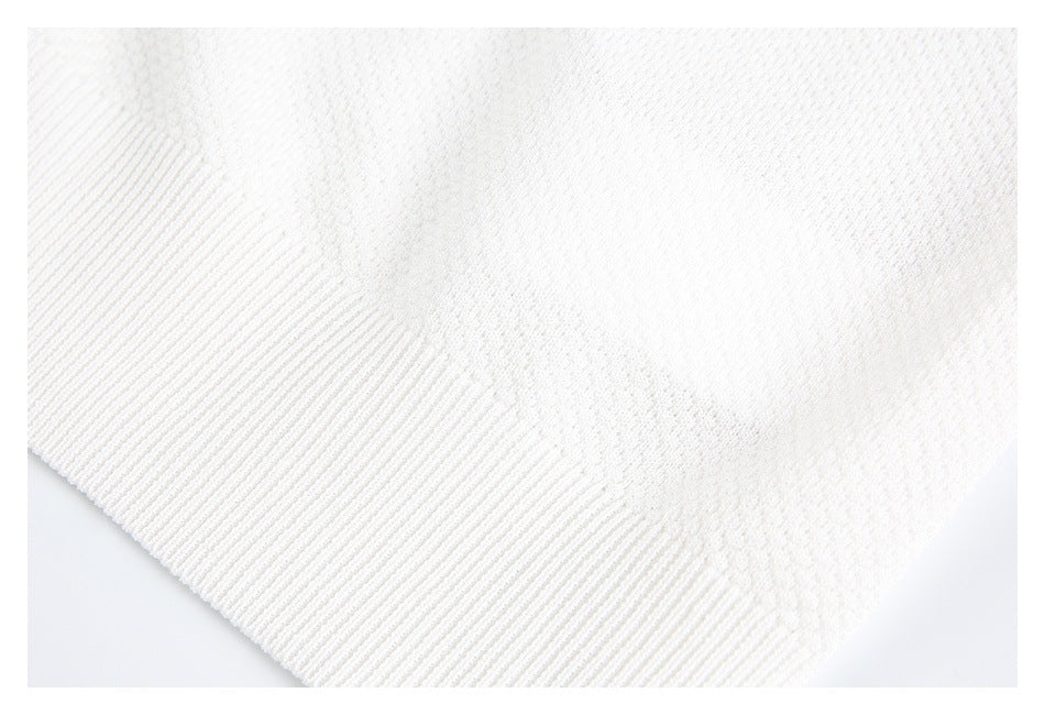 Close-up of the white knit garment's ribbed hem and textured fabric.