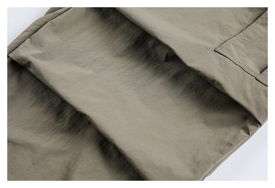 Close-up of olive-gray garment fabric with a stitched seam and folded edge.