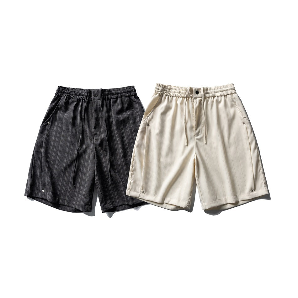 Two flat-laid pairs of striped shorts, one charcoal and one cream, with elastic waistbands and drawstrings.