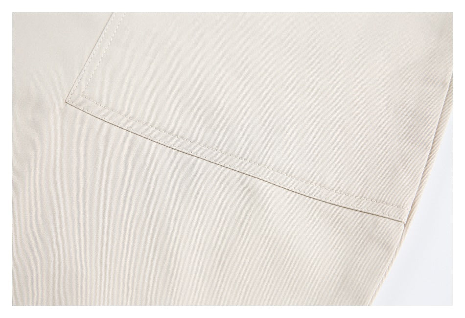 Close-up of a rectangular stitched pocket on light beige pants.