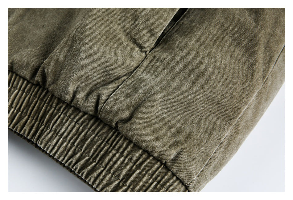 Close-up of an olive-gray garment's gathered elastic hem and stitched panel seams.