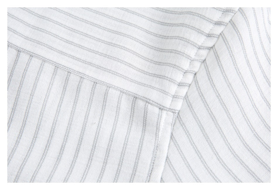 Close-up of intersecting seams on white fabric with fine gray stripes.