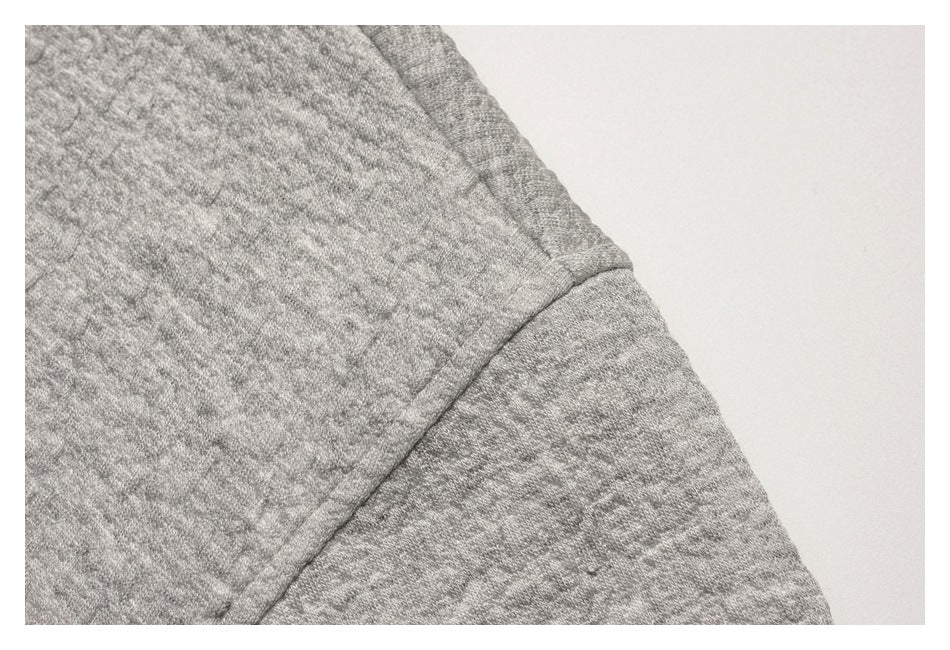 Close-up of a seam across the shoulder of a gray textured sweatshirt.