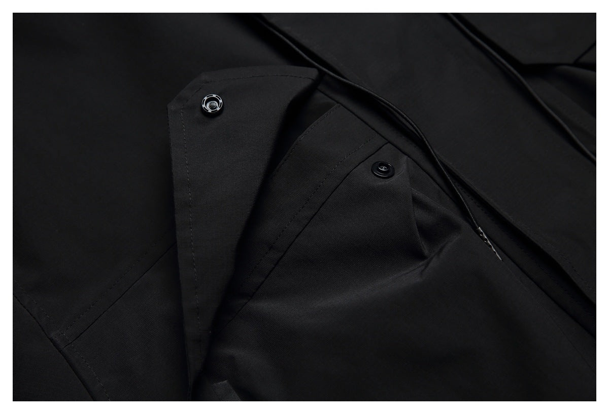 Close-up of a black garment's overlapping panels with two snap fasteners and a drawcord.