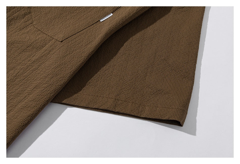 Close-up of the brown shirt's lower side and hem laid flat.