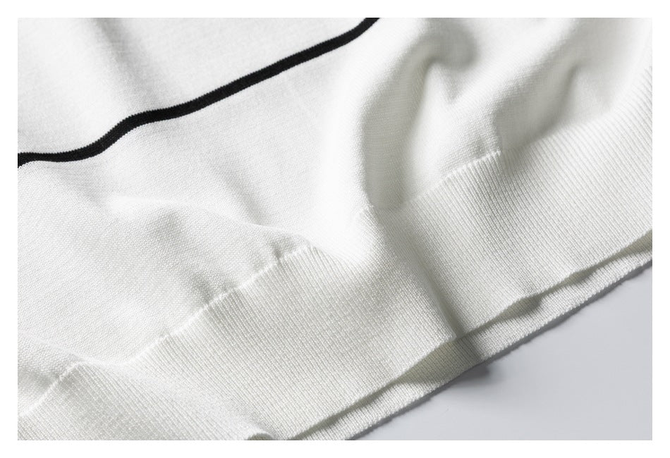 Close-up of the white sweater's ribbed hem and knit surface, with a thin black stripe above.
