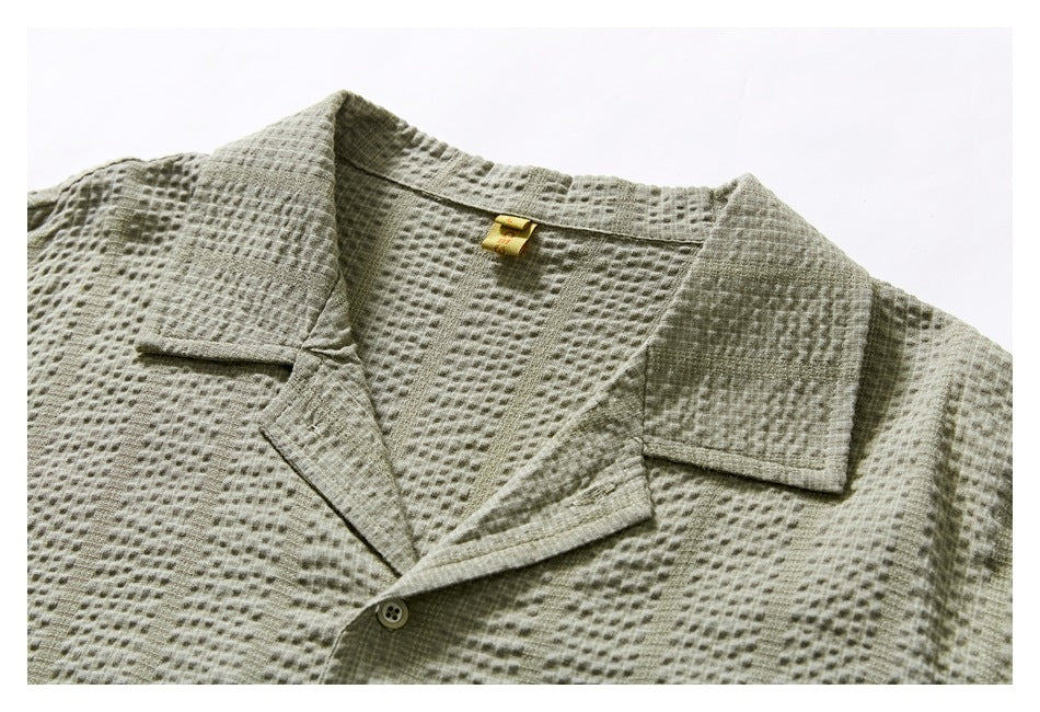 Close-up of the sage-gray shirt's notched collar, textured fabric, front placket, and button.