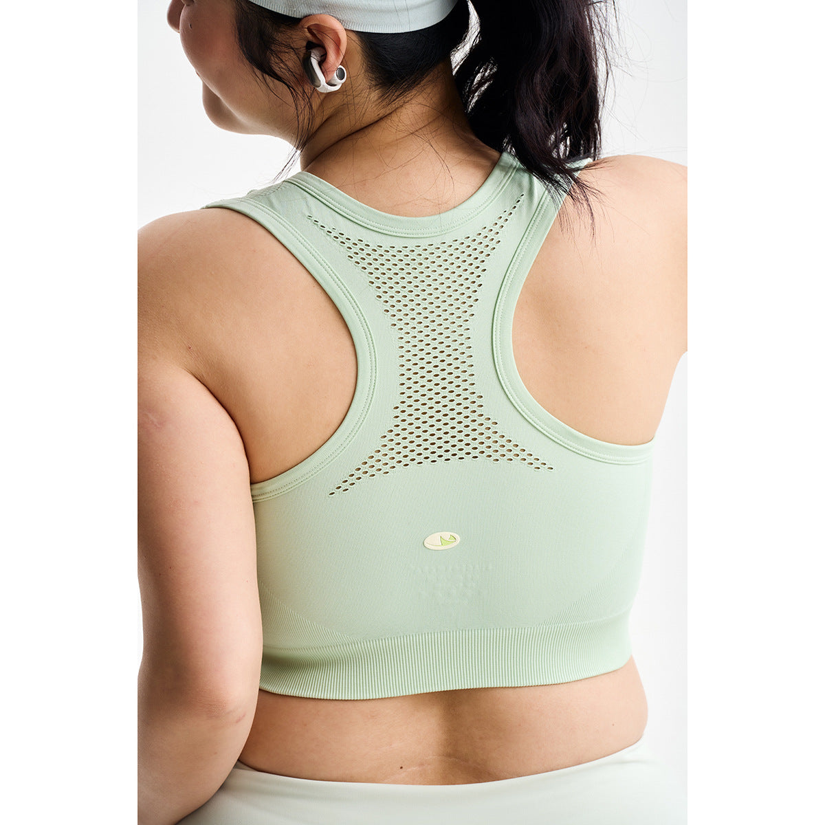 Close-up of a mint-green racerback sports bra with a perforated mesh back panel and wide ribbed band.