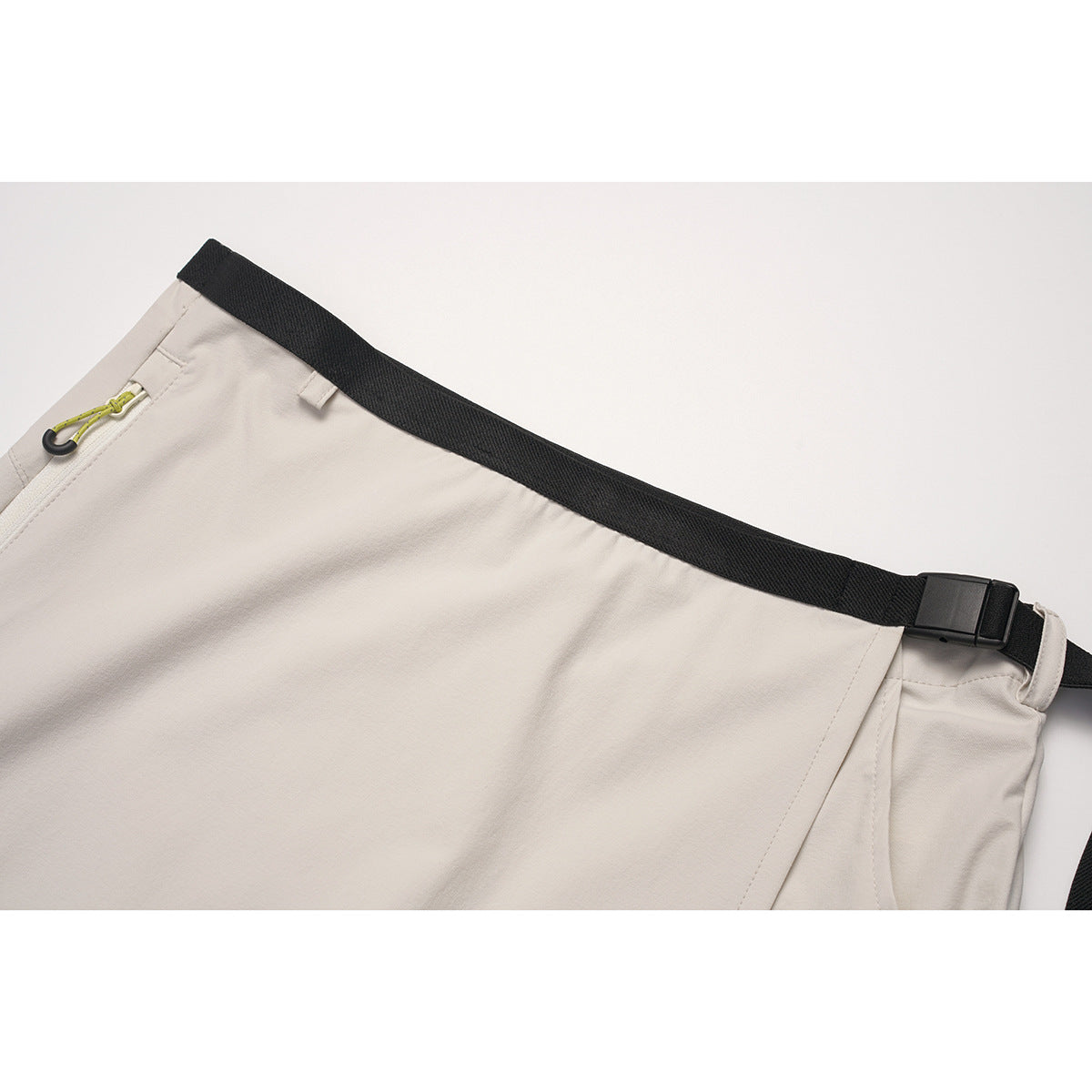 Close-up of the beige skirt's black waist strap and buckle, with a small zip pocket.