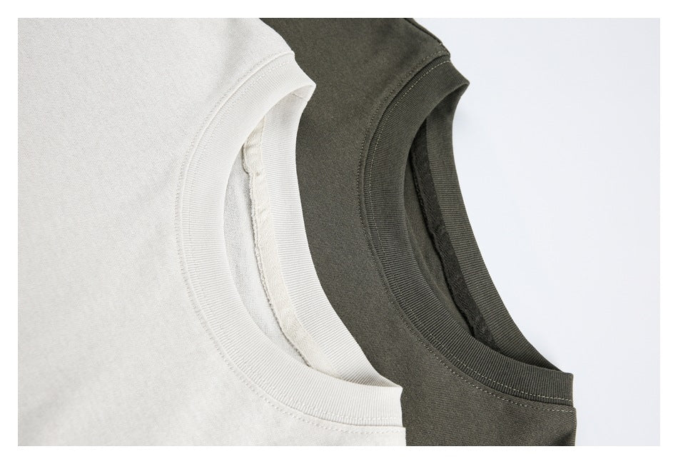 Close-up of the ribbed crew necklines and inner seams of off-white and dark olive T-shirts.
