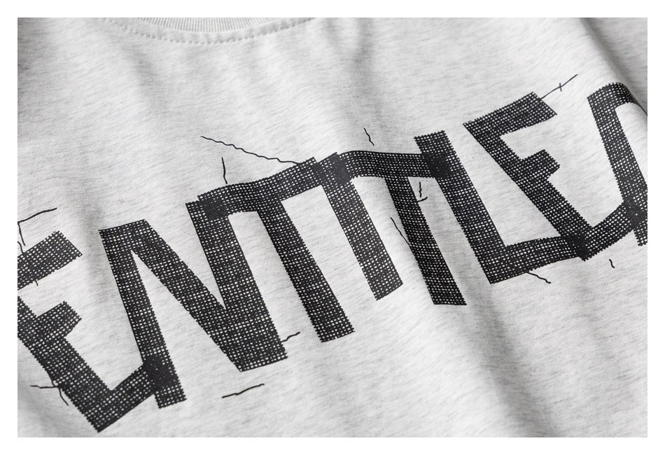 Close-up of large distressed black lettering printed across light heather-gray T-shirt fabric.