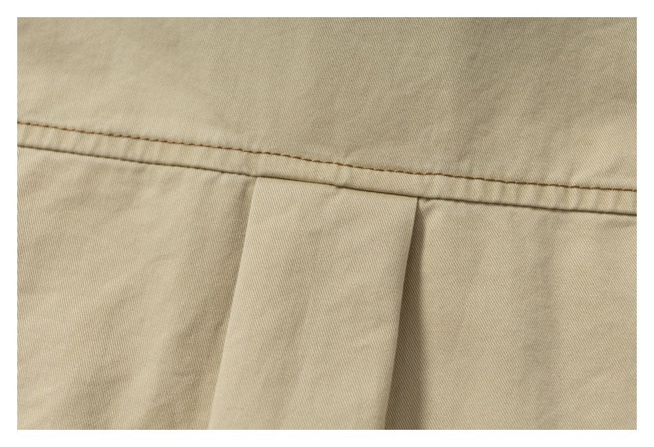 Close-up of a tan garment's stitched seam and folded fabric panel.