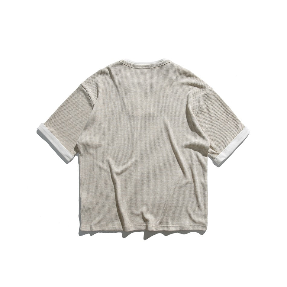 Back view of a light beige textured short-sleeve shirt with white sleeve cuffs.