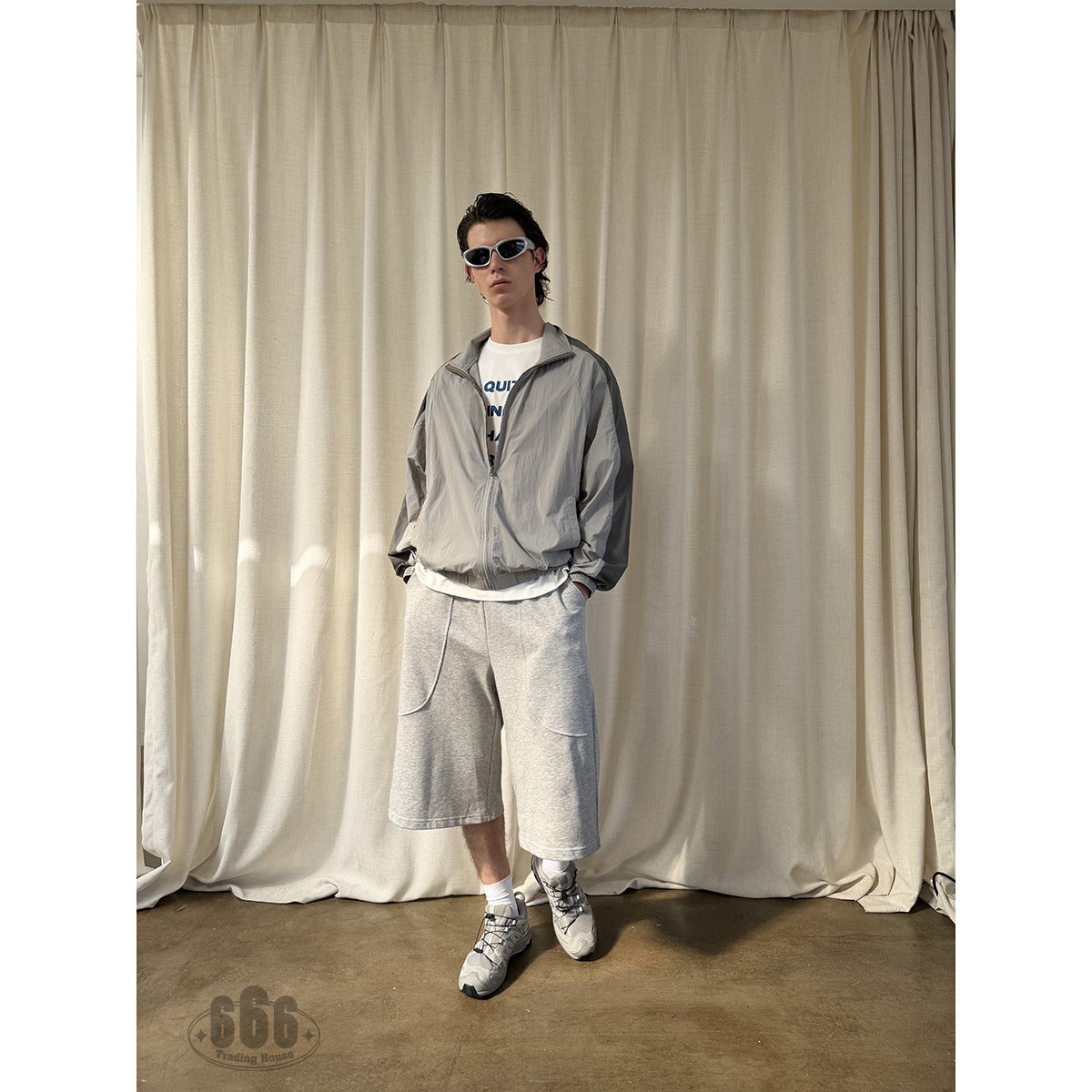 Front view of a model wearing loose light gray knee-length shorts with curved front pockets.