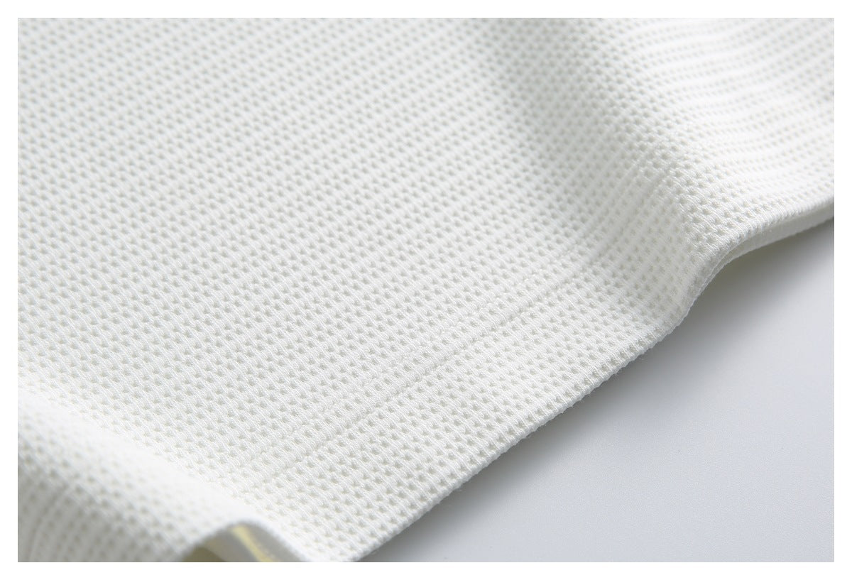 Close-up of white knit fabric and a finished garment edge, showing the textured stitches.
