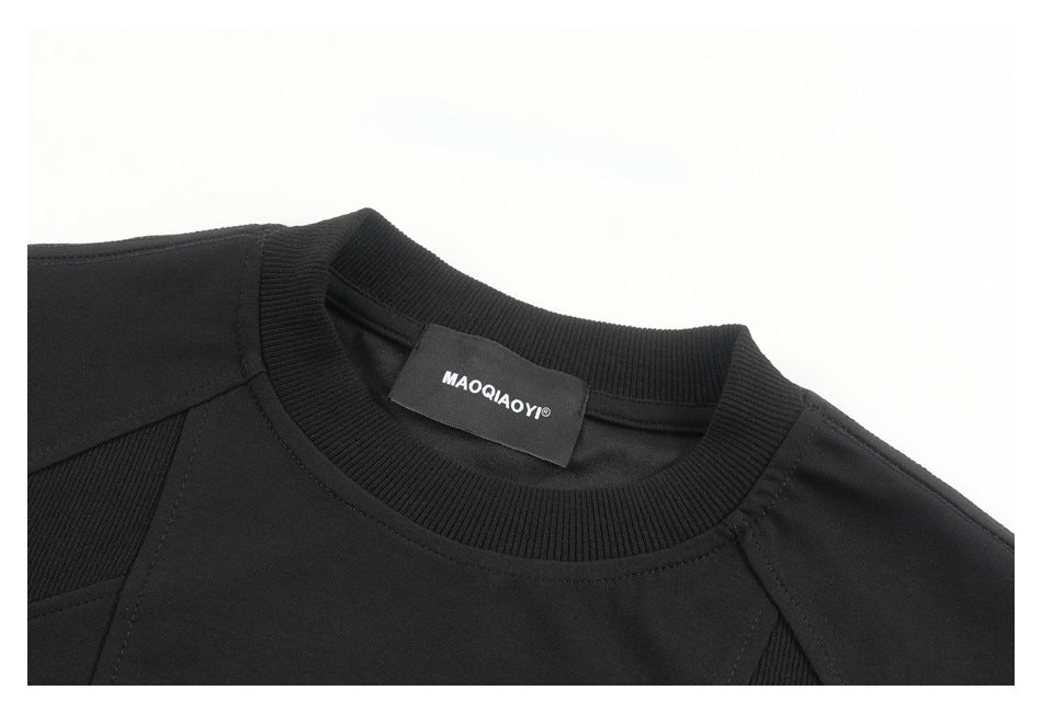 Close-up of a black T-shirt's ribbed crew neck, shoulder seams, and sewn neck label.
