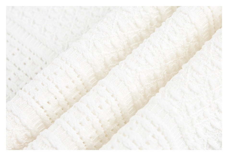 Close-up of white textured knit fabric with raised ribbed and looped patterns.