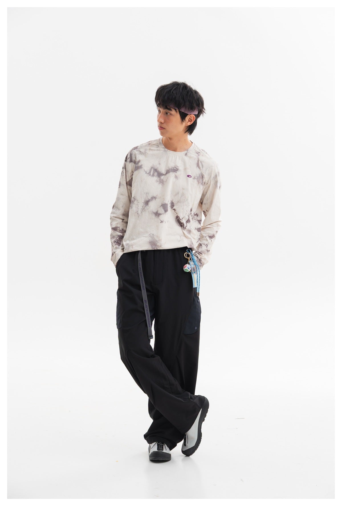 Model wearing a cream and gray tie-dye long-sleeve shirt with black cargo pants, shown full-length from the front.
