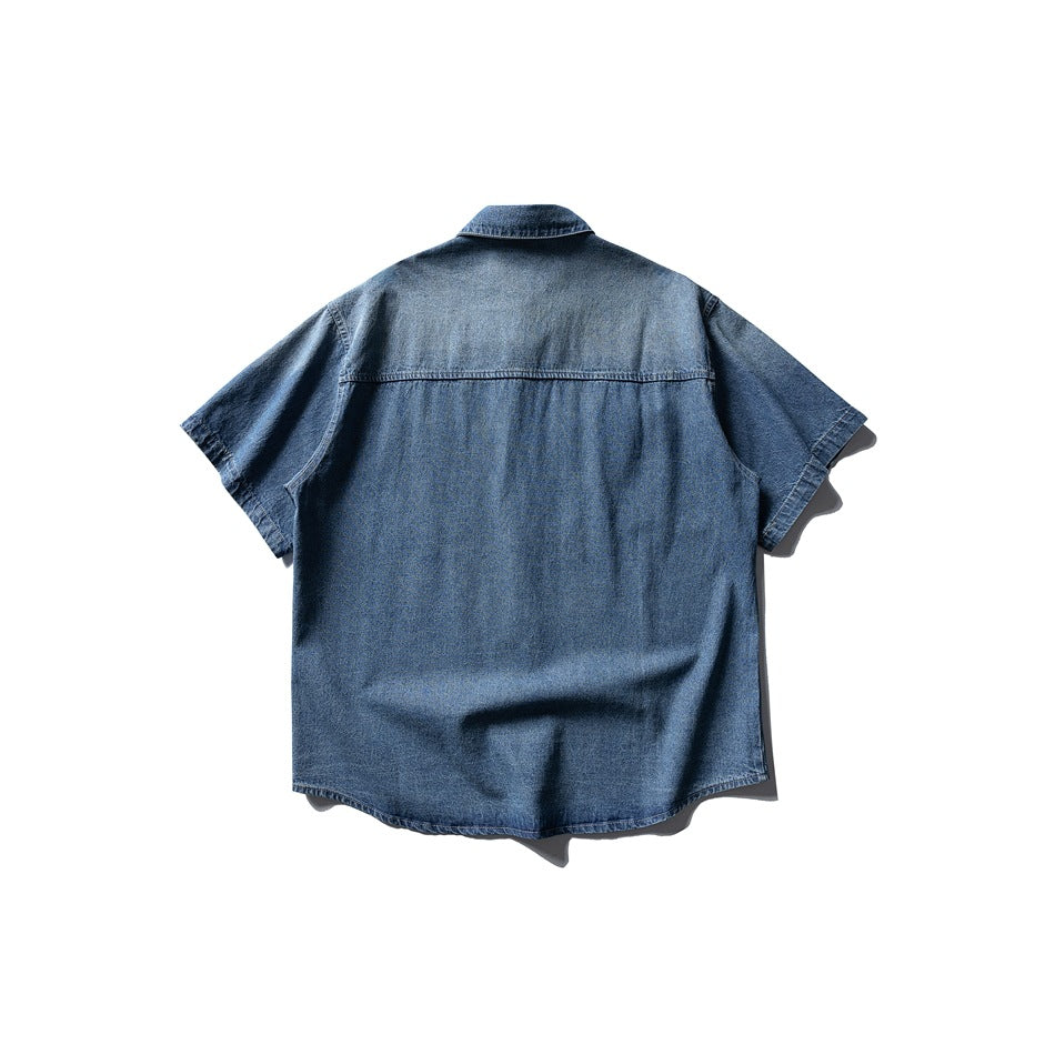 Back view of a faded blue denim short-sleeve shirt with a back yoke seam and a slightly curved hem