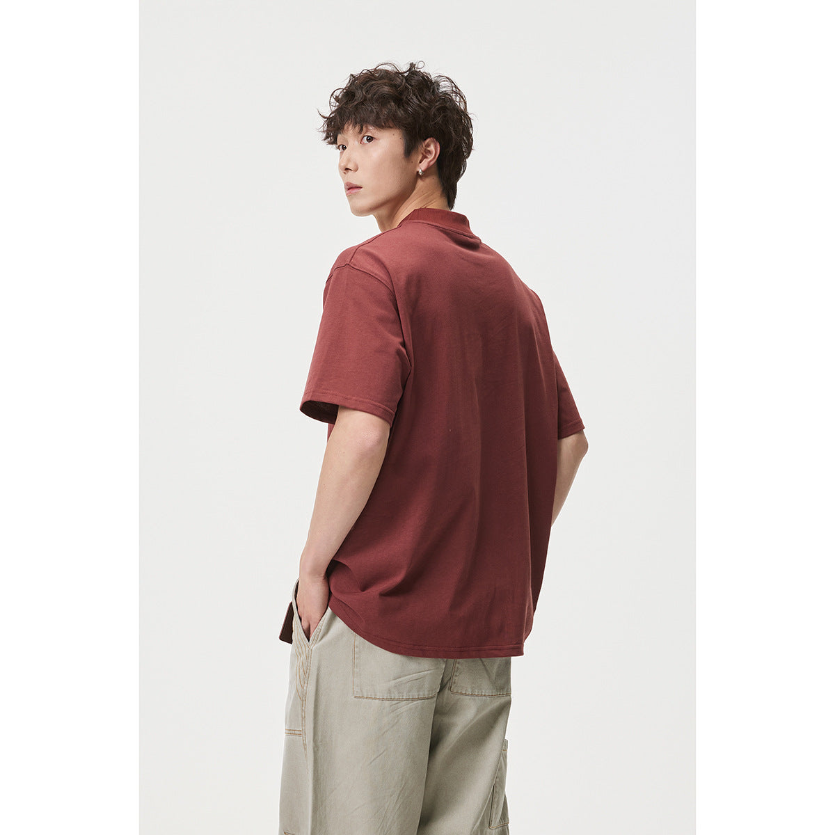 Model shown from a rear three-quarter angle wearing a loose burgundy short-sleeve T-shirt.