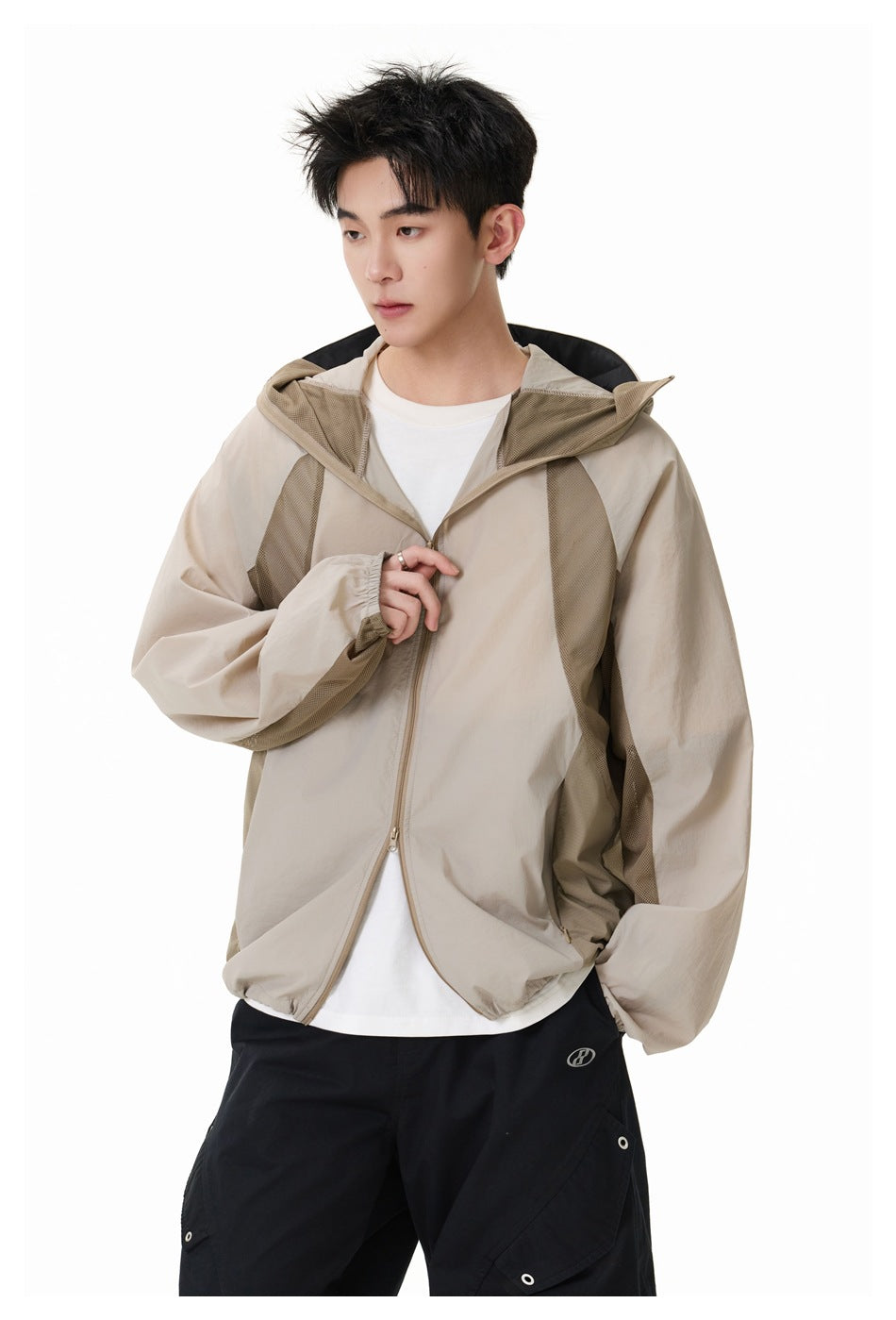 Model wearing an unzipped light beige hooded jacket with contrasting mesh panels over a white shirt.