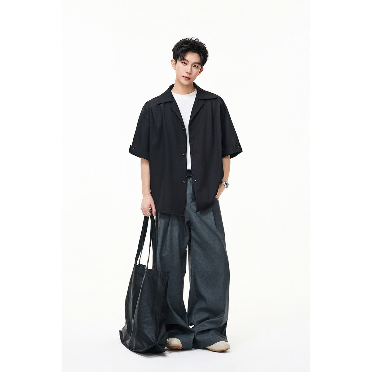 Model wearing an oversized black short-sleeve button-up shirt over a white tee.