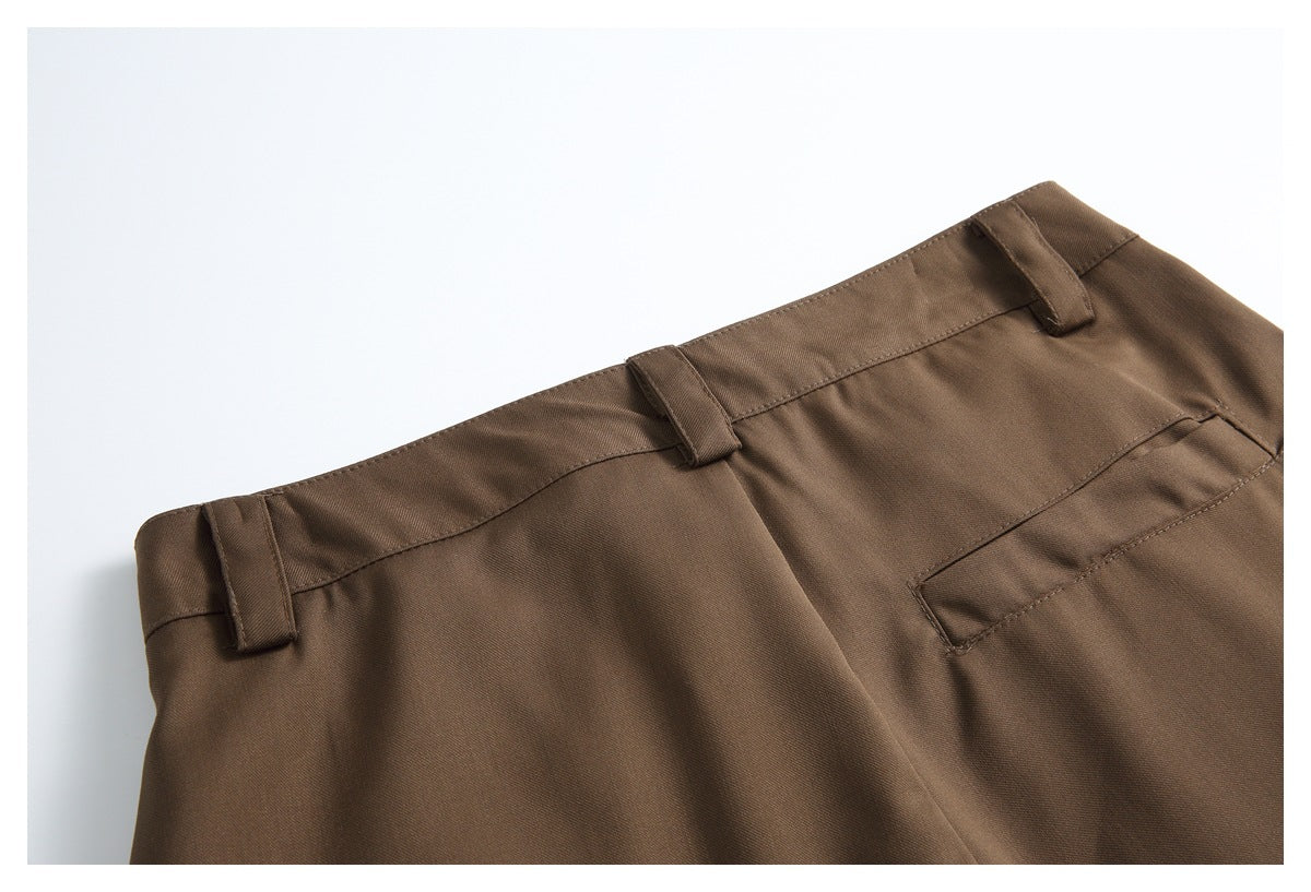 Close-up of brown trousers showing the waistband, belt loops, and a back pocket.