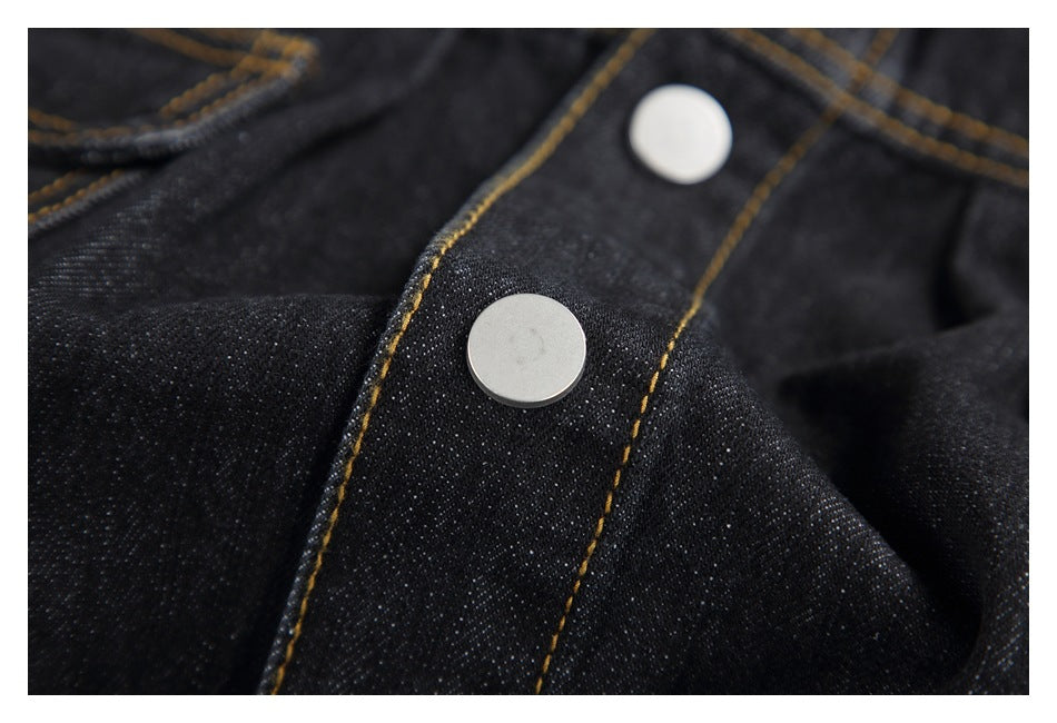 Close-up of silver snap buttons and gold-stitched placket on dark denim.