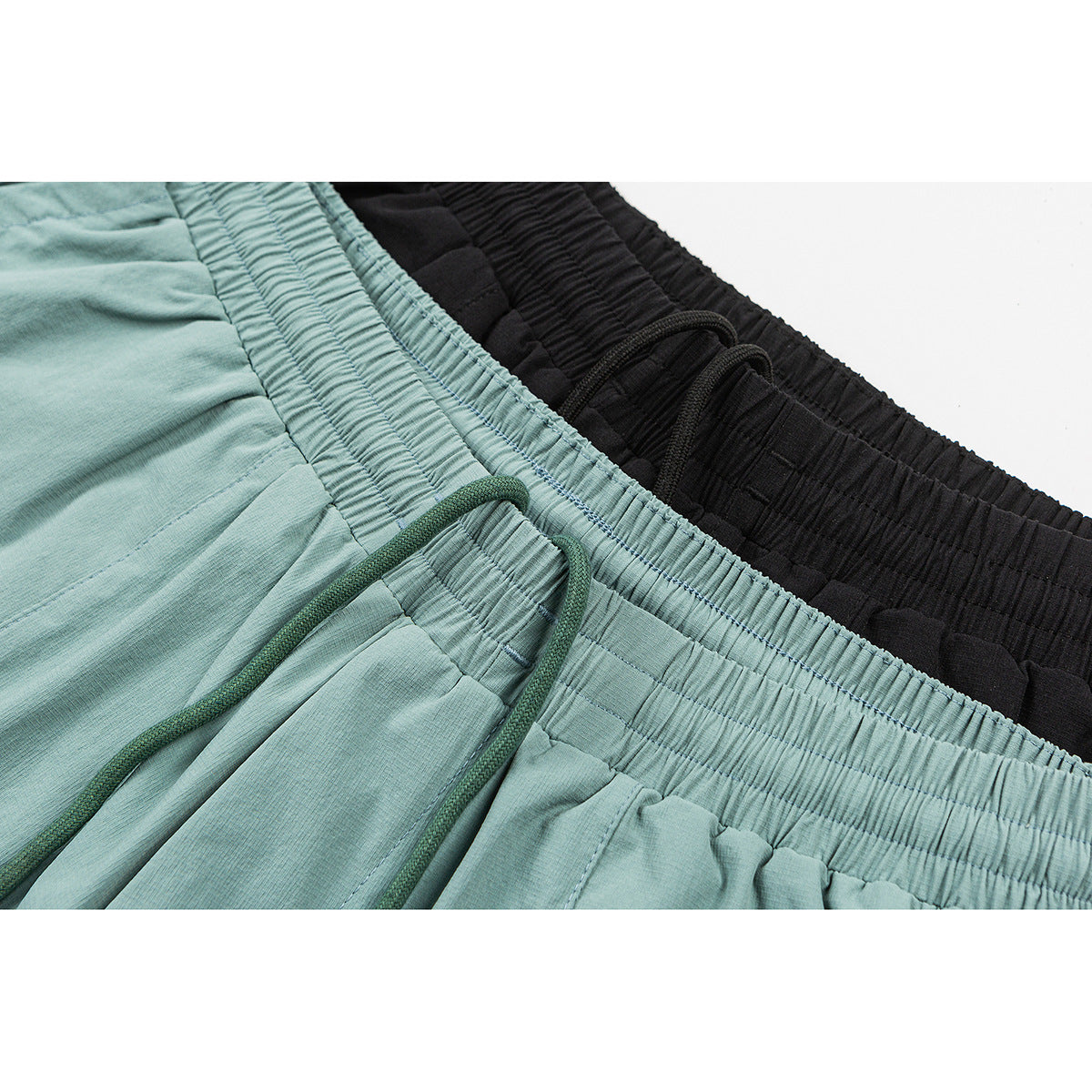 Close-up of aqua and black shorts showing gathered elastic waistbands and drawstrings.