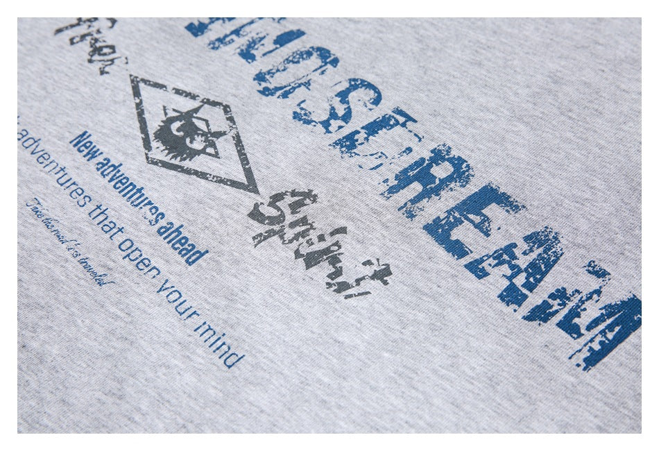 Angled close-up of the distressed blue and dark graphic printed on a heather gray top.