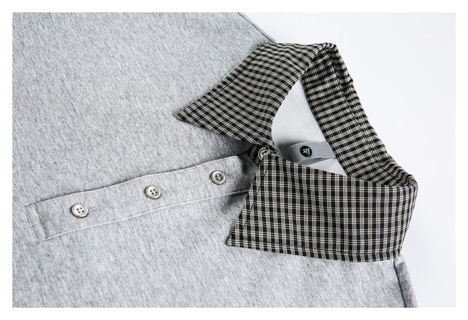 Close-up of a gray top with a black-and-white checked collar and three-button placket.