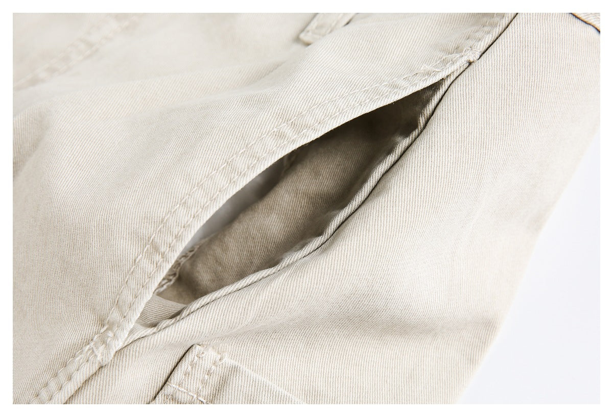 Close-up of a slanted pocket opening and stitching on light beige pants.