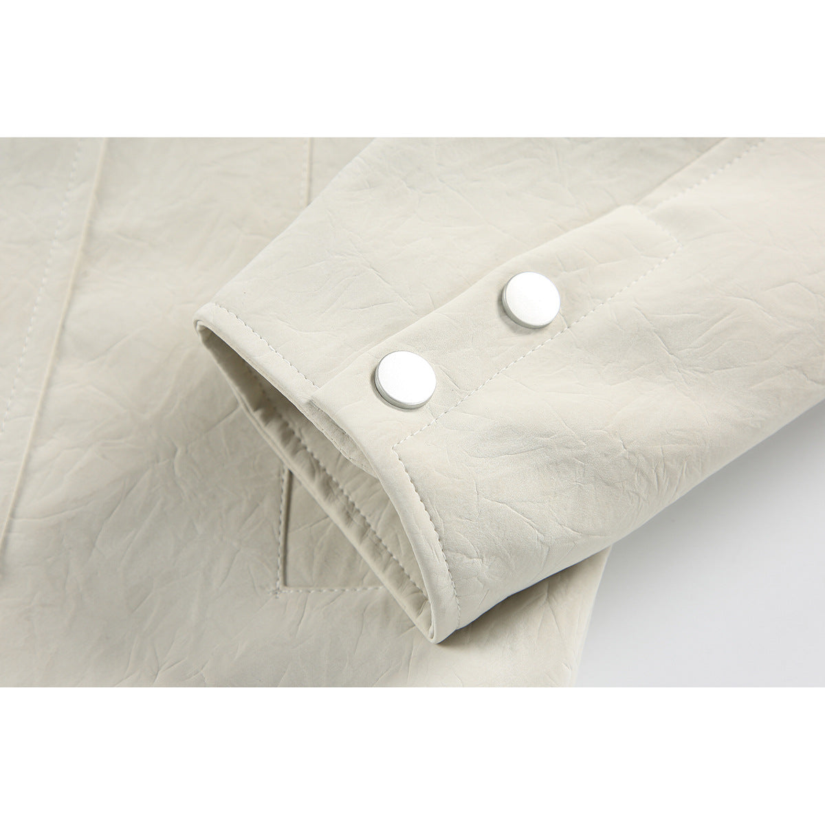 Close-up of an ivory jacket sleeve cuff with two silver snap buttons.