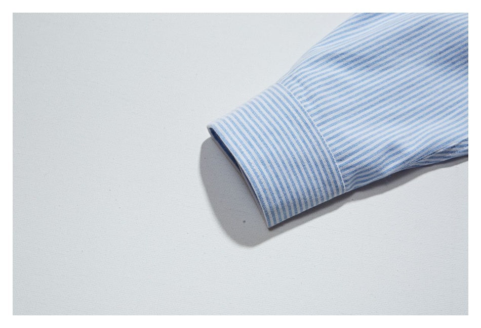 Close-up of a blue-and-white striped shirt sleeve ending in a buttonless cuff.