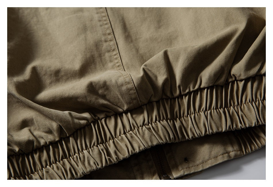 Close-up of a gathered elastic hem and nearby zipper on a khaki garment.