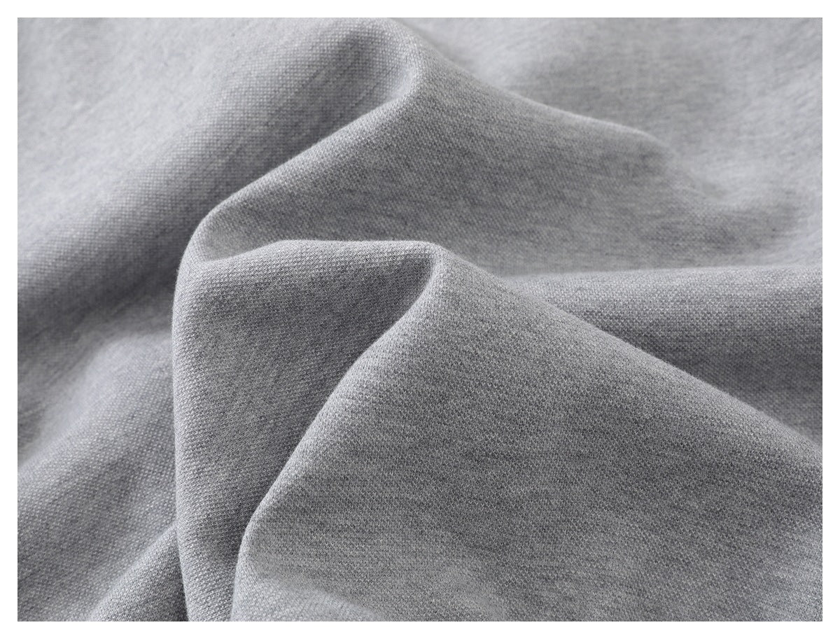 Extreme close-up of light gray garment fabric draped in soft folds.