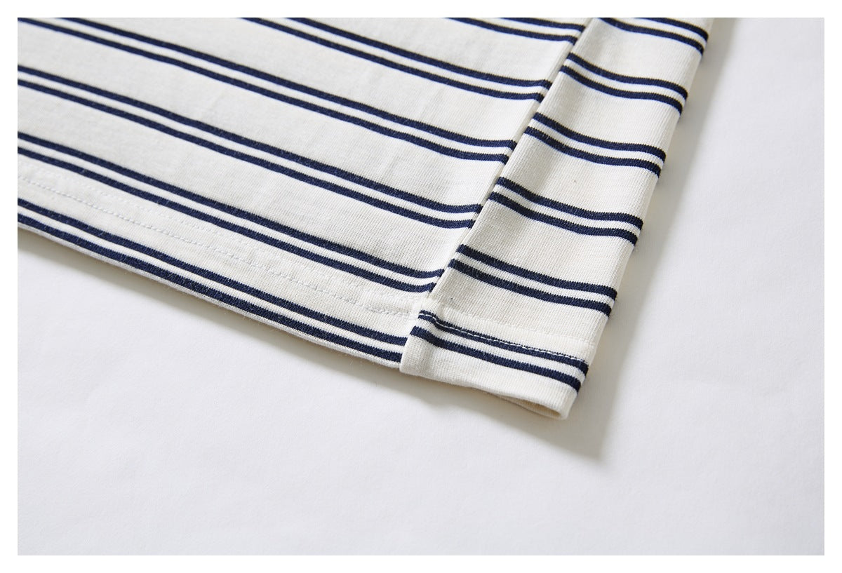 Close-up of a striped ivory garment's stitched hem and sleeve edge.
