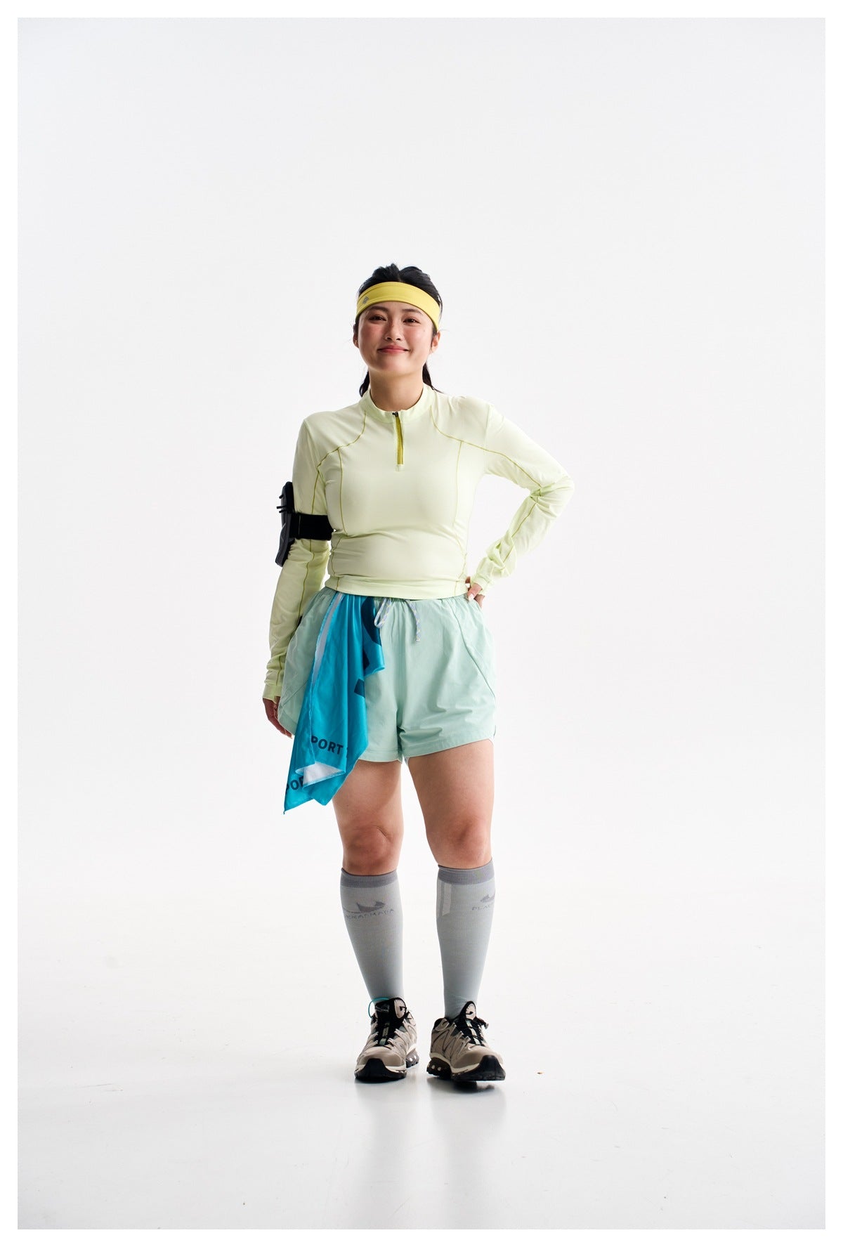 Full-length model in a pale yellow quarter-zip top, mint shorts, gray knee-high socks, and running shoes.