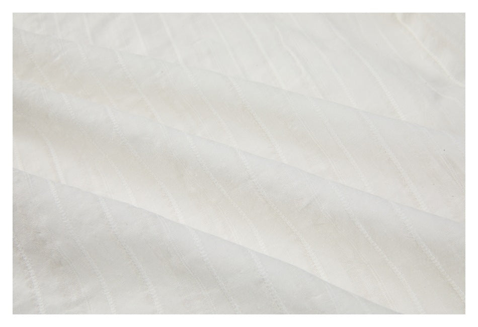 Close-up of off-white fabric with subtle diagonal woven stripes.