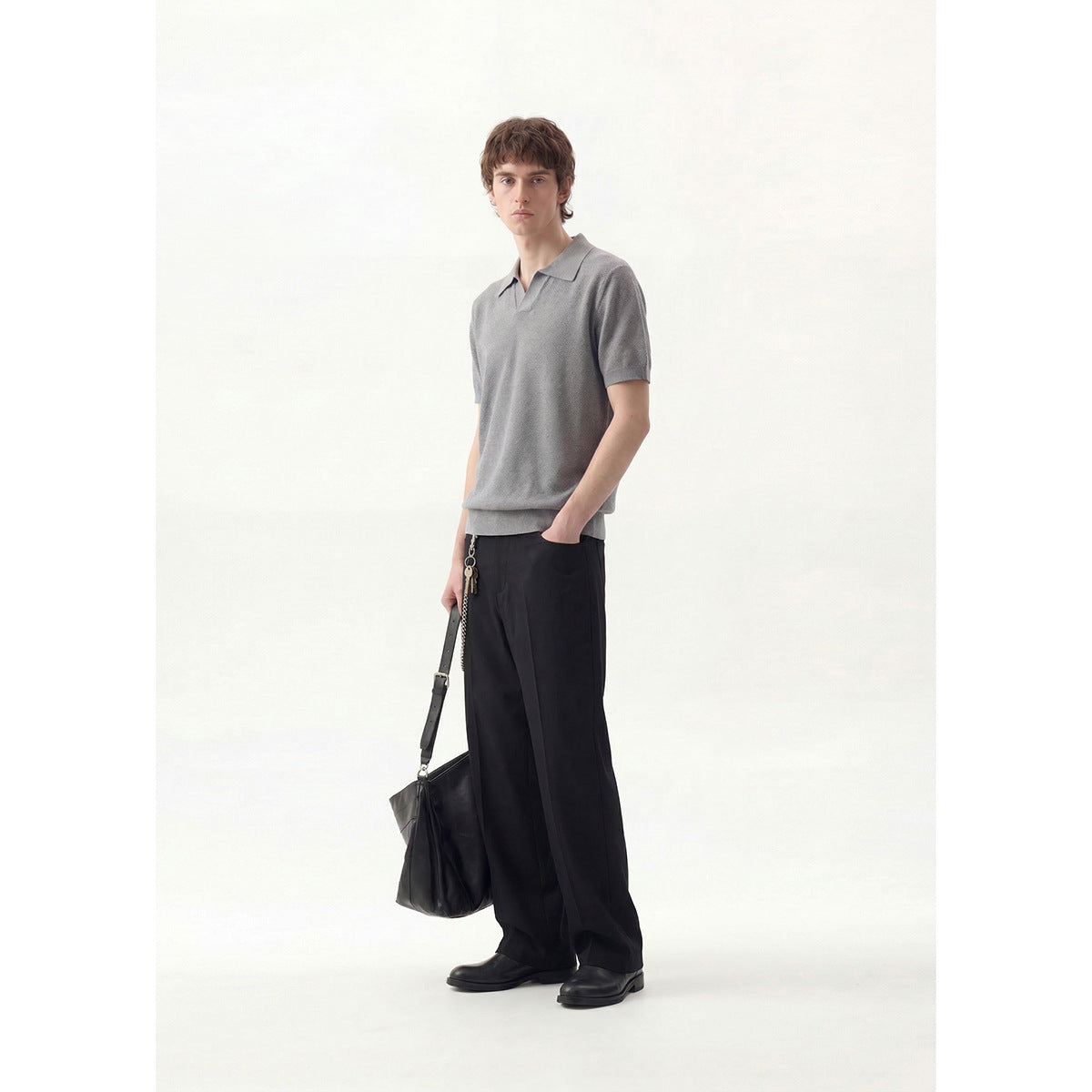 Model wearing a gray short-sleeve collared pullover with black wide-leg trousers, shown full length from the front.