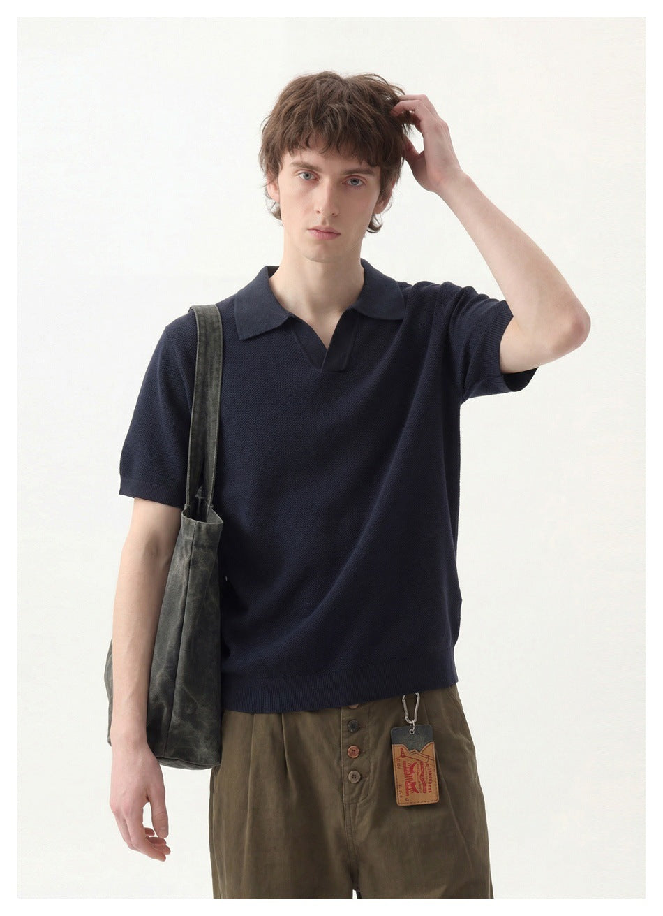 Model wearing a dark navy short-sleeve collared pullover, shown from the front in a waist-up view.