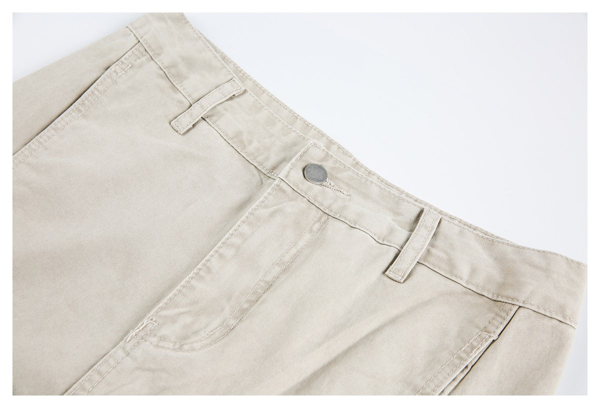 Close-up of light beige trousers showing the waistband, belt loops, metal button, and front pocket.